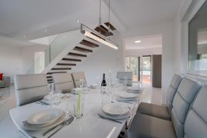 a white dining room with a table and a staircase at Villa Čimić in Krk