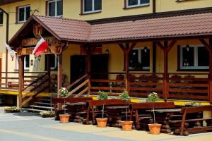 a building with tables and potted plants in front of it at Usługi Hotelowe 17 Zwiedzanie Muzeum Kresów Gratis in Ostrów Mazowiecka