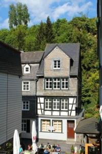 ein großes weißes und schwarzes Haus mit Leuten davor in der Unterkunft Maison Riviére in Monschau