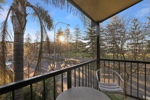 un balcone con tavolo, sedie e palma. di Bayview Apartments Glenelg a Adelaide