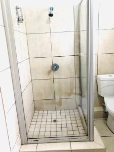 a shower stall in a bathroom with a toilet at The Eden Lodge Verulam in Verulam