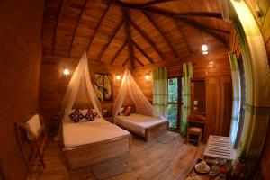 a bedroom with a large bed and a large window at Mutu Village treehouse tourist board approved bungalow in Habarana