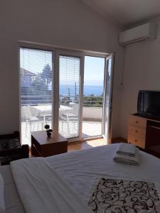 Schlafzimmer mit einem Bett, einem TV und einem Balkon in der Unterkunft Vila Idila in Ohrid