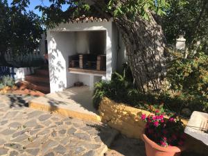 a white entrance to a house with a tree and flowers at Finca La Rosalía in Setenil