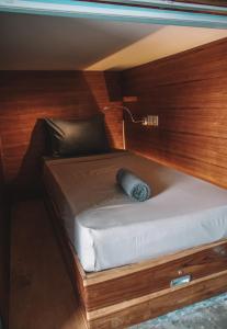 a small bed in a room with wooden walls at Kaniu Capsule Hostel in Kuta Lombok