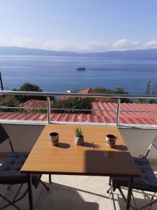 einen Holztisch auf einem Balkon mit Blick auf das Wasser in der Unterkunft Vila Idila in Ohrid