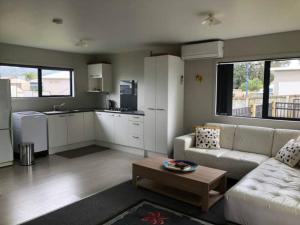 a living room with a white couch and a kitchen at Whitianga Kiwi Bach in Whitianga