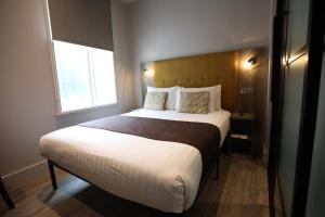 a bedroom with a large white bed with a window at Euston Square Hotel in London