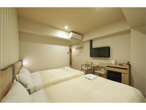 a hotel room with two beds and a television at Sotetsu Fresa Inn Kamakura-Ofuna Higashiguchi in Kamakura