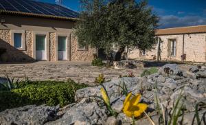 a house with rocks and a yellow flower in the yard at La Mela Di Venere in Palazzolo Acreide