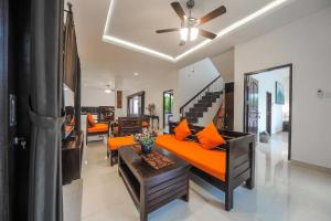 a living room with an orange couch and a ceiling fan at Villa Rindik Sanur in Sanur
