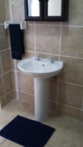 La salle de bains est pourvue d'un lavabo blanc et d'un tapis noir. dans l'établissement LANGEBAAN, à Langebaan