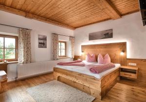 Un dormitorio con una gran cama de madera con almohadas rosas en Stubnerbauer, en Bad Hofgastein