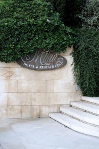a sign for a hotel and restaurant on a wall with stairs at Hotel Milan in Pula