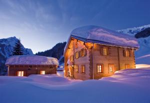 a large wooden building with snow on top of it at Vital Chalets in Schröcken