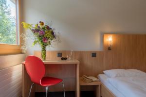 a bedroom with a red chair and a vase of flowers at Sport Resort Fiesch, Garni Aletsch in Fiesch