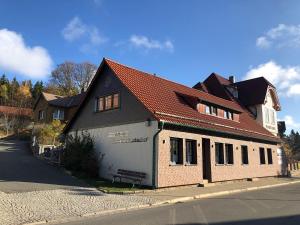 un bâtiment avec un toit rouge sur le côté d'une rue dans l'établissement Ferienwohnungen Zum Brockenbäcker in Schierke, à Schierke