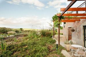 a patio with a table and chairs in a garden at Vineyard Views Country House in Riebeek-Kasteel