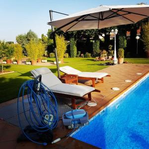 uma piscina com um guarda-sol e espreguiçadeiras ao lado em Villamercedes II em Villamayor
