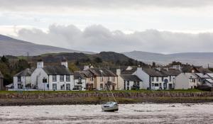 a small boat in the water in front of houses at The Inn at Ravenglass in Ravenglass