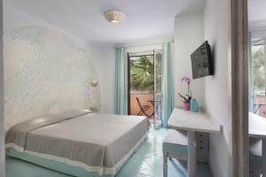 sypialnia z łóżkiem, stołem i oknem w obiekcie Hotel Corallaro w mieście Santa Teresa Gallura