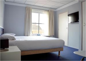 a bedroom with a bed and a window at Belgische Loodsensociëteit in Vlissingen