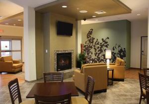 a living room with a fireplace and a table and chairs at Sleep Inn & Suites Garden City in Garden City
