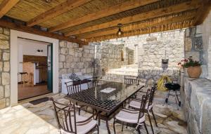un patio con mesa, sillas y pared de piedra. en Villa Maestral en Brsečine