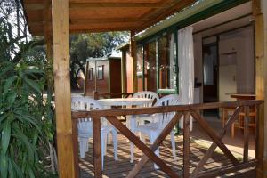 una terraza con sillas blancas y una mesa en una casa en Camping Relax Ge en Montrás