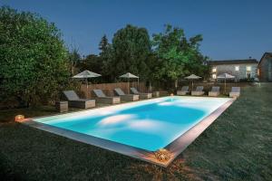 a swimming pool with chairs and umbrellas in a yard at Le Petit Bouchon in Parcoul