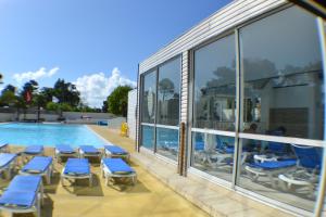 una piscina con tumbonas azules junto a un edificio en Le Sherwood - Mobil-Home, en Saint-Jean-de-Monts