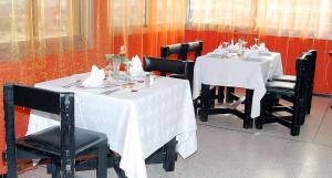 un comedor con mesas blancas y sillas negras en HOTEL CONTINENTAL Khénifra en Khenifra