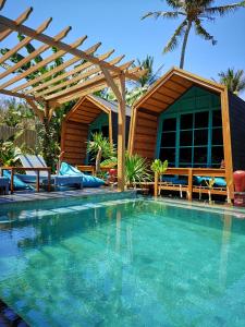 a swimming pool with a wooden pergola and a house at Absolute Villa in Gili Trawangan