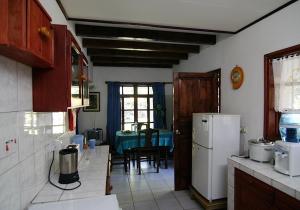 a kitchen with a table and a white refrigerator at La Rocaille in Baie Lazare Mahé