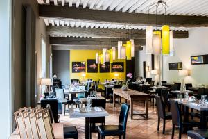 uma sala de jantar com mesas, cadeiras e luzes em Hostellerie la Ferme du Poulet et son restaurant em Villefranche-sur-Saône