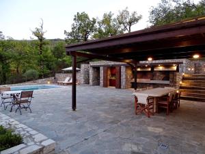 eine Terrasse mit einem Tisch, Stühlen und einem Pool in der Unterkunft Τείχιο Βίλα - Tihio Villa - Πετρόχτιστη βίλα in Tíkhion