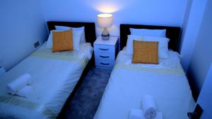2 camas individuales en una habitación con luz azul en A Modern, Comfy Newly Remodeled 2bd House en Barking