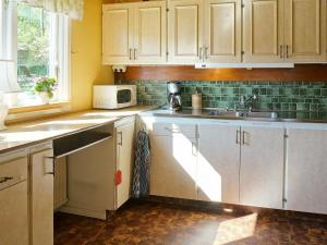 een keuken met witte kasten, een wastafel en een magnetron bij 6 person holiday home in ULLARED in Ullared
