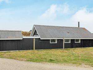 una casa con una valla negra delante de ella en 6 person holiday home in Vejers Strand, en Vejers Strand