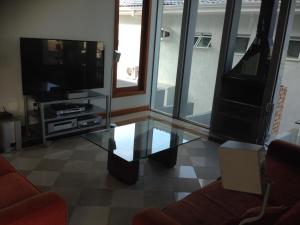 a living room with a tv and a glass table at Hangaroa in Bertioga