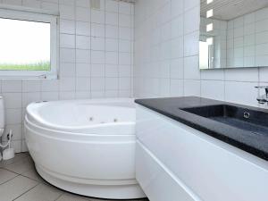 a white bathroom with a tub and a sink at Four-Bedroom Holiday home in Tarm 3 in Hemmet