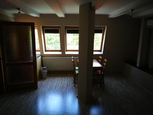 a room with a table and chairs and windows at Tornyos Panzió és Étterem in Matrafured