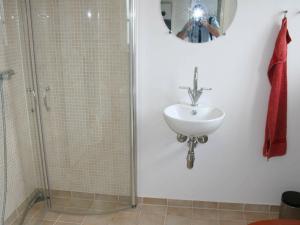 un homme prenant une photo d'une salle de bains avec lavabo et douche dans l'établissement 4 person holiday home in Aakirkeby, à Åkirkeby