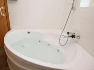 a white bath tub with a shower in a bathroom at 12 person holiday home in H jslev in Bøstrup