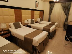 una camera d'albergo con due letti e una televisione di Diyaralmashaer Al-Hadiyah Hotel a La Mecca