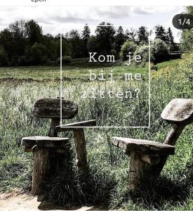 two stone benches sitting in a field with a sign at Hotel,Herberg & Appartementen de Smidse in Epen