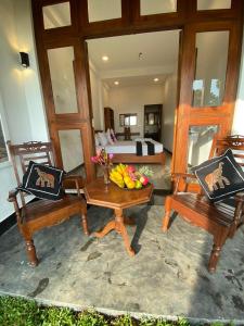 um quarto com duas cadeiras de madeira e uma cama em Ocean Breeze Villa em Matara