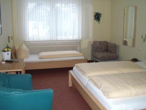 維林根的住宿－彩虹旅館，客房设有两张床、一张桌子和一把椅子。