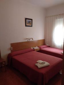 Habitación de hotel con 2 camas con sábanas rojas en PENSION MIRAFLORES en Zaragoza