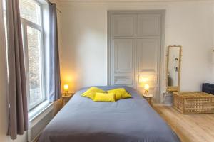 1 dormitorio con 1 cama con 2 almohadas amarillas en Les Augustins en Amiens